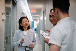 Three business professionals discussing teamwork strategies in a modern office hallway.
